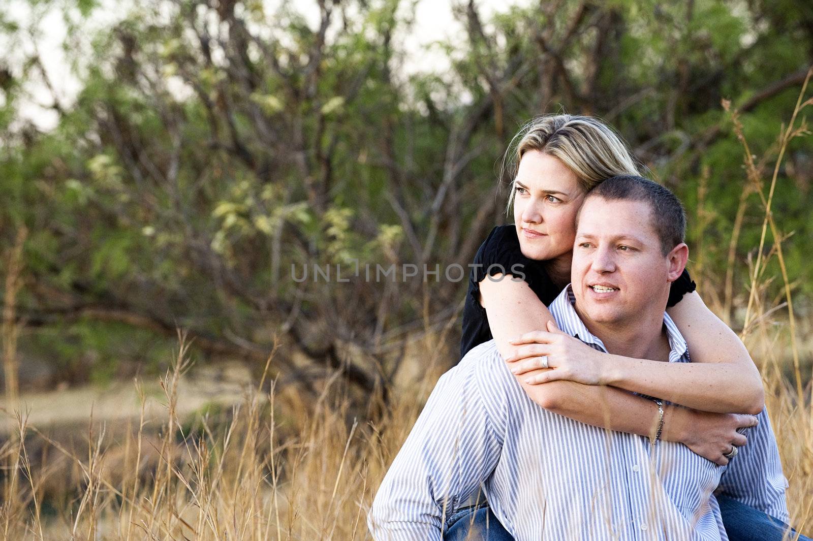 young sexy beautiful blond couple carrying and smiling in long grass at daytime in summer