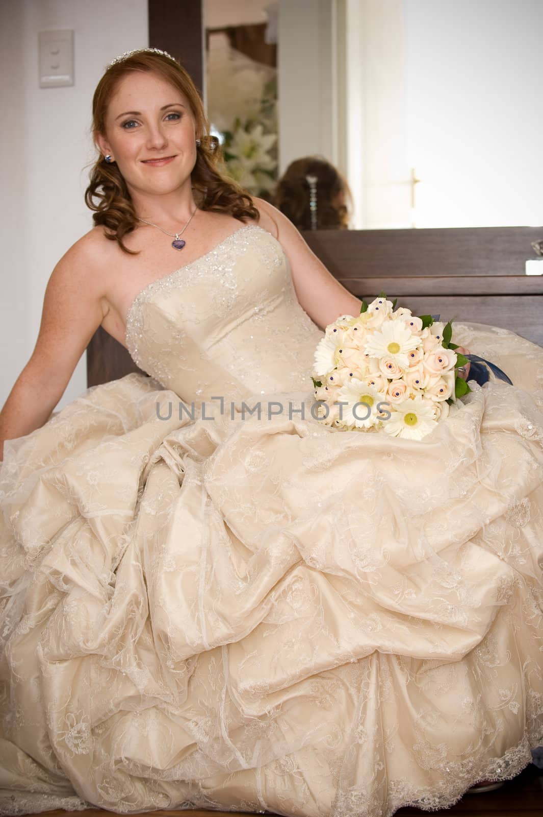 bride sitting leaning on arm smiling and holding white bouquet by Ansunette