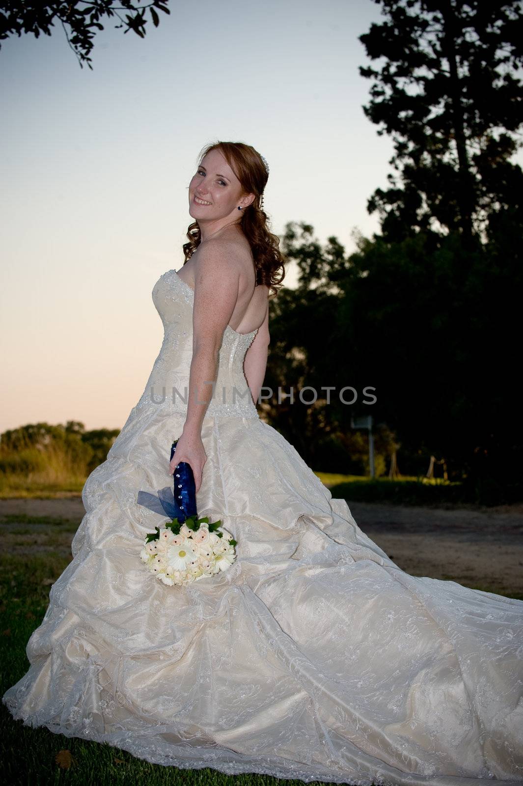 blond head sexy beautiful just married bride standing with white bouquet outside at dusk