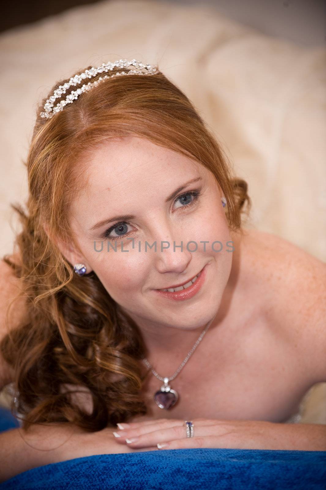 red head sexy beautiful bride laying down on her elbows with cleavage visible and leaning on her hands whilst smiling