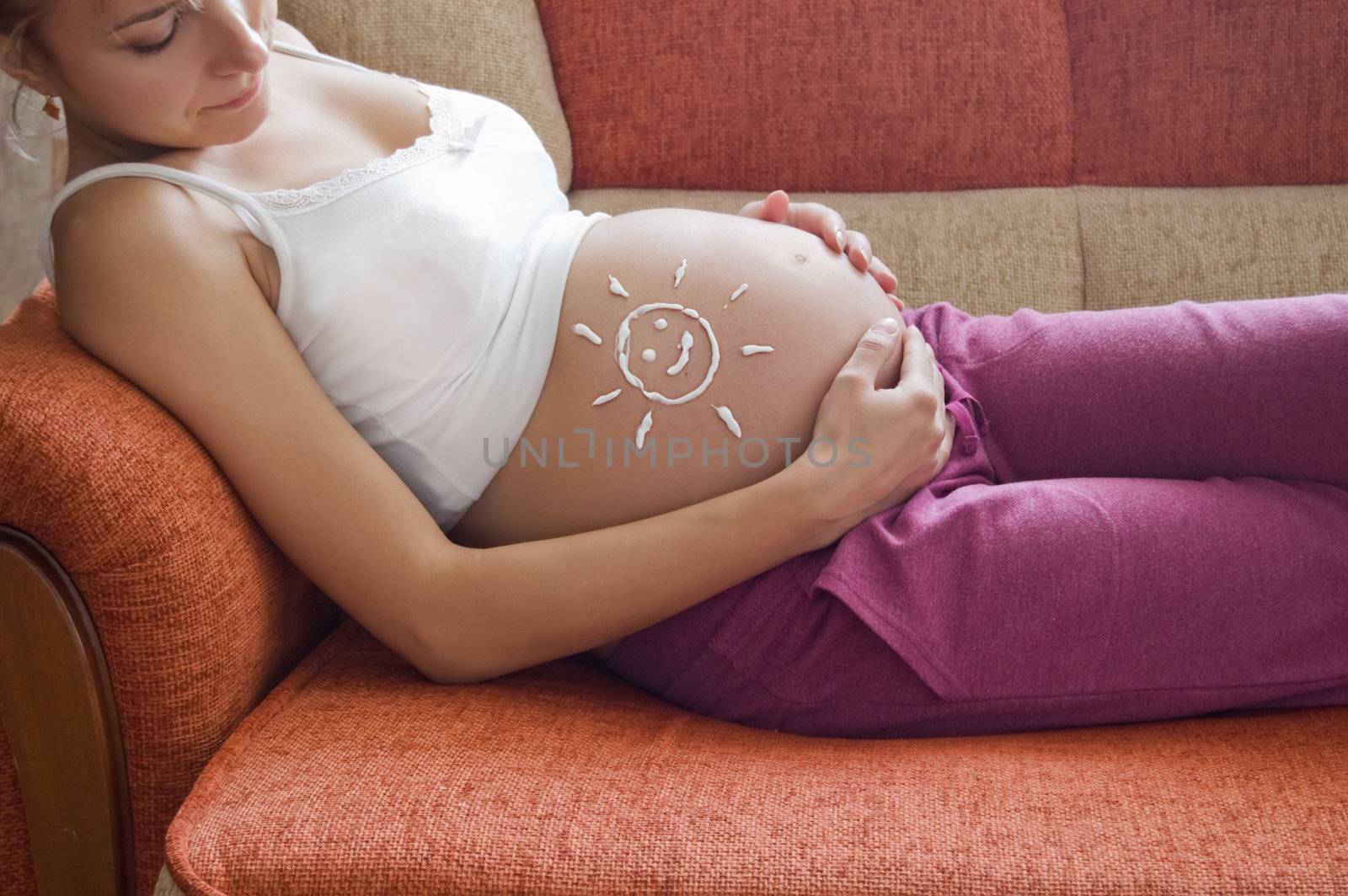 Pregnant woman belly with drawn sun by creme