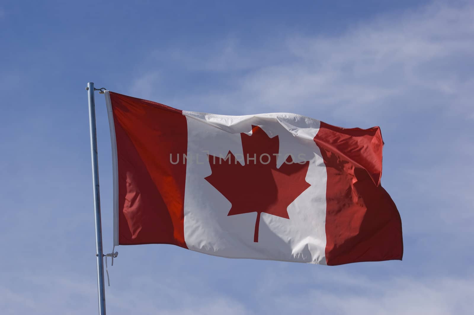 Canadian flag blowing in the wind against blue sky