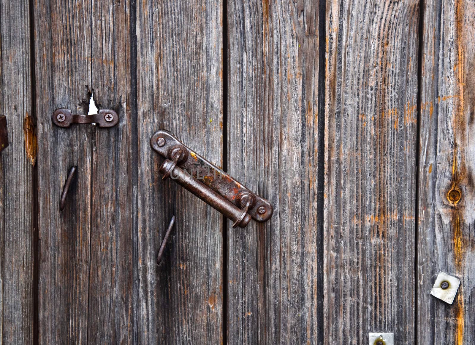 Old rusty door handle close. A fragment of a wooden door with a latch.