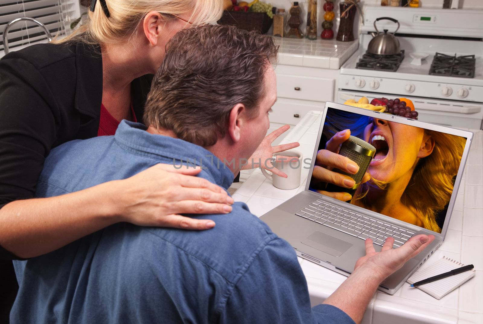 Couple In Kitchen Using Laptop with Singing Woman on the Screen.