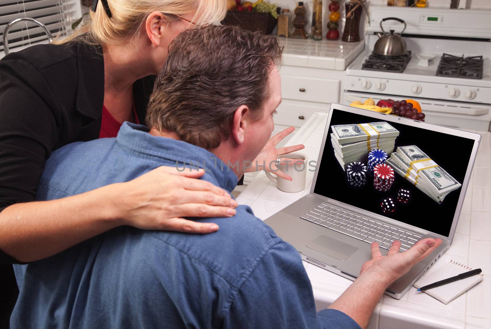 Couple In Kitchen Using Laptop with Stacks of Money and Poker Chips on the Screen.