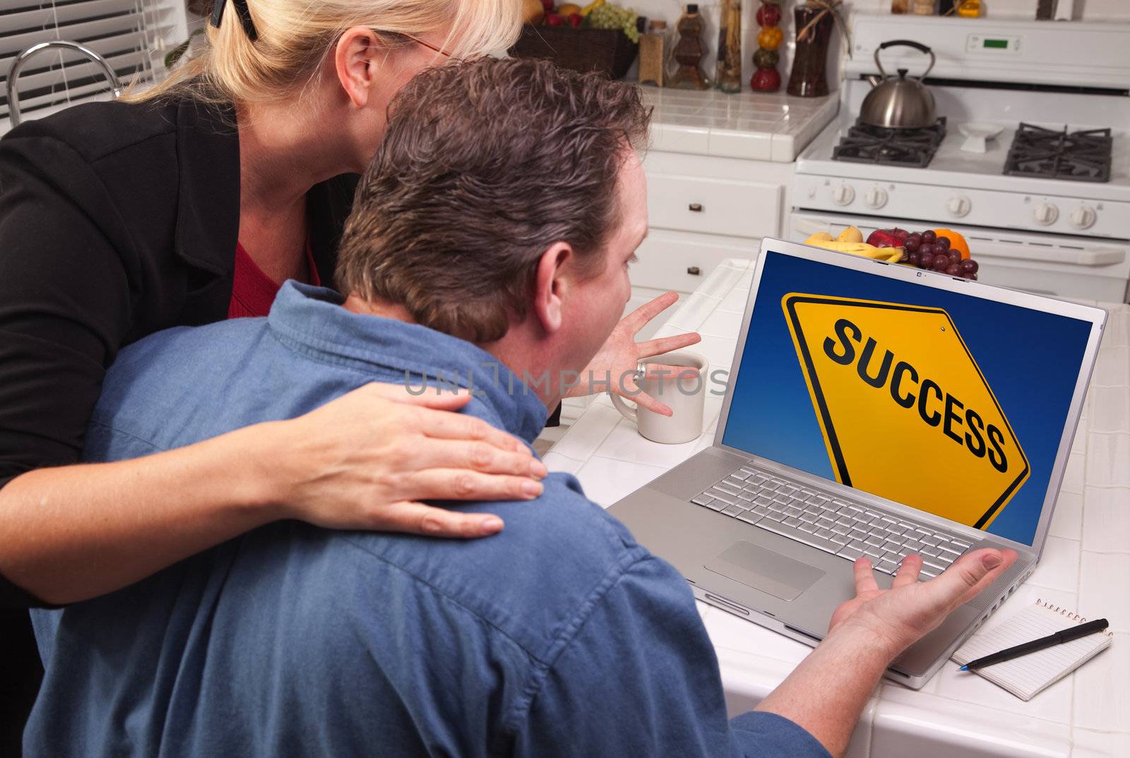 Couple In Kitchen Using Laptop with Yellow Success Road Sign on the Screen.