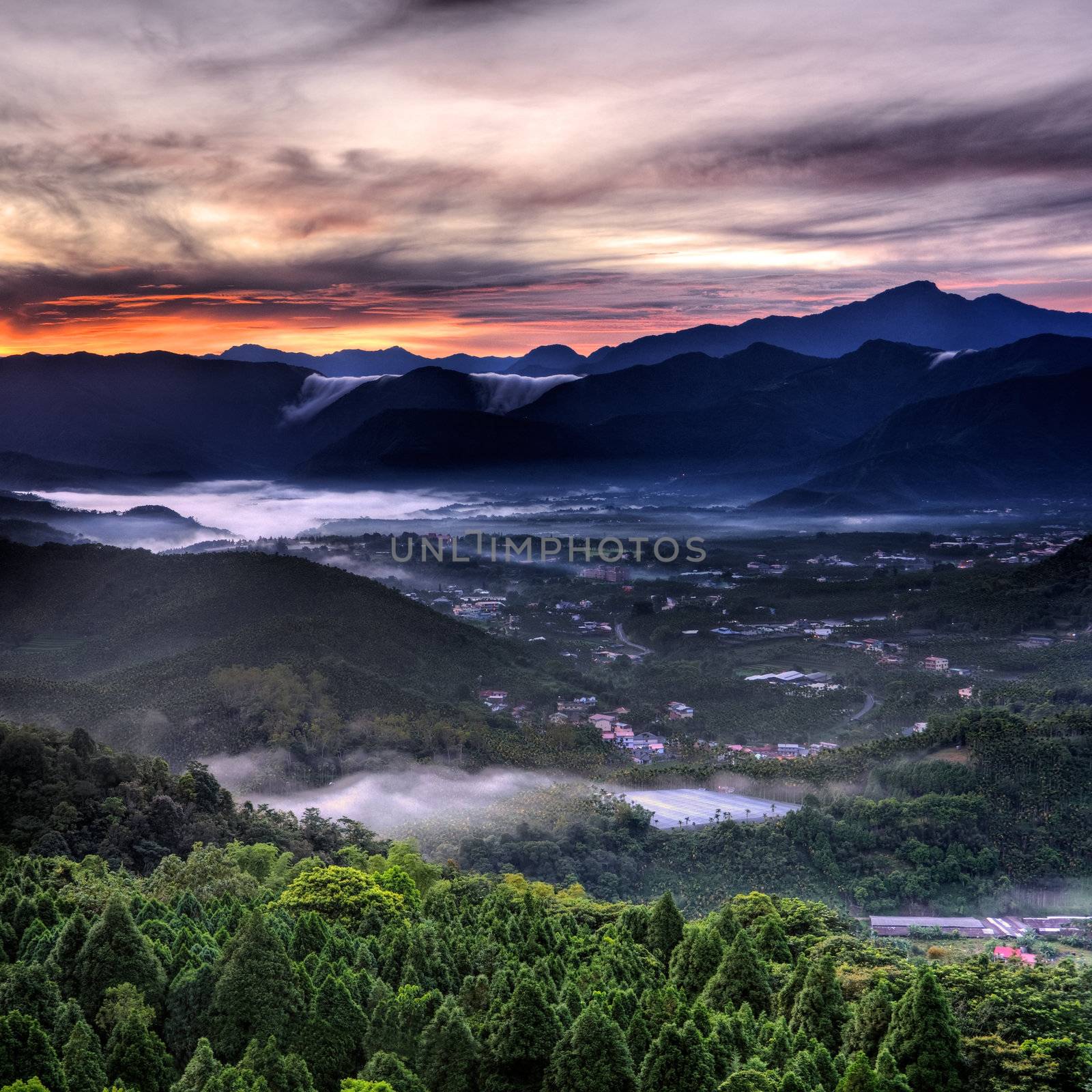 landscape of morning in countryside with dramatic sky and mist in forest.