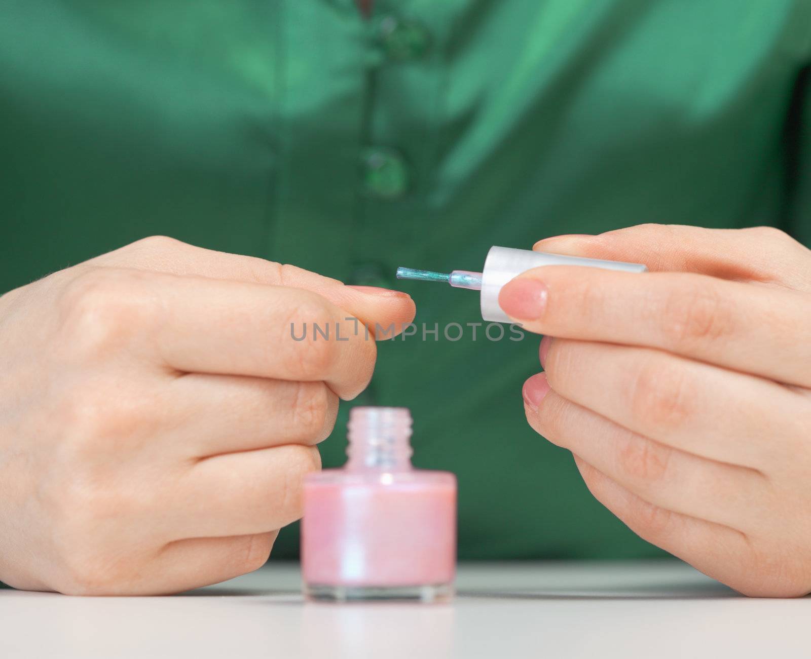 The woman varnishes nails - a close up of hands