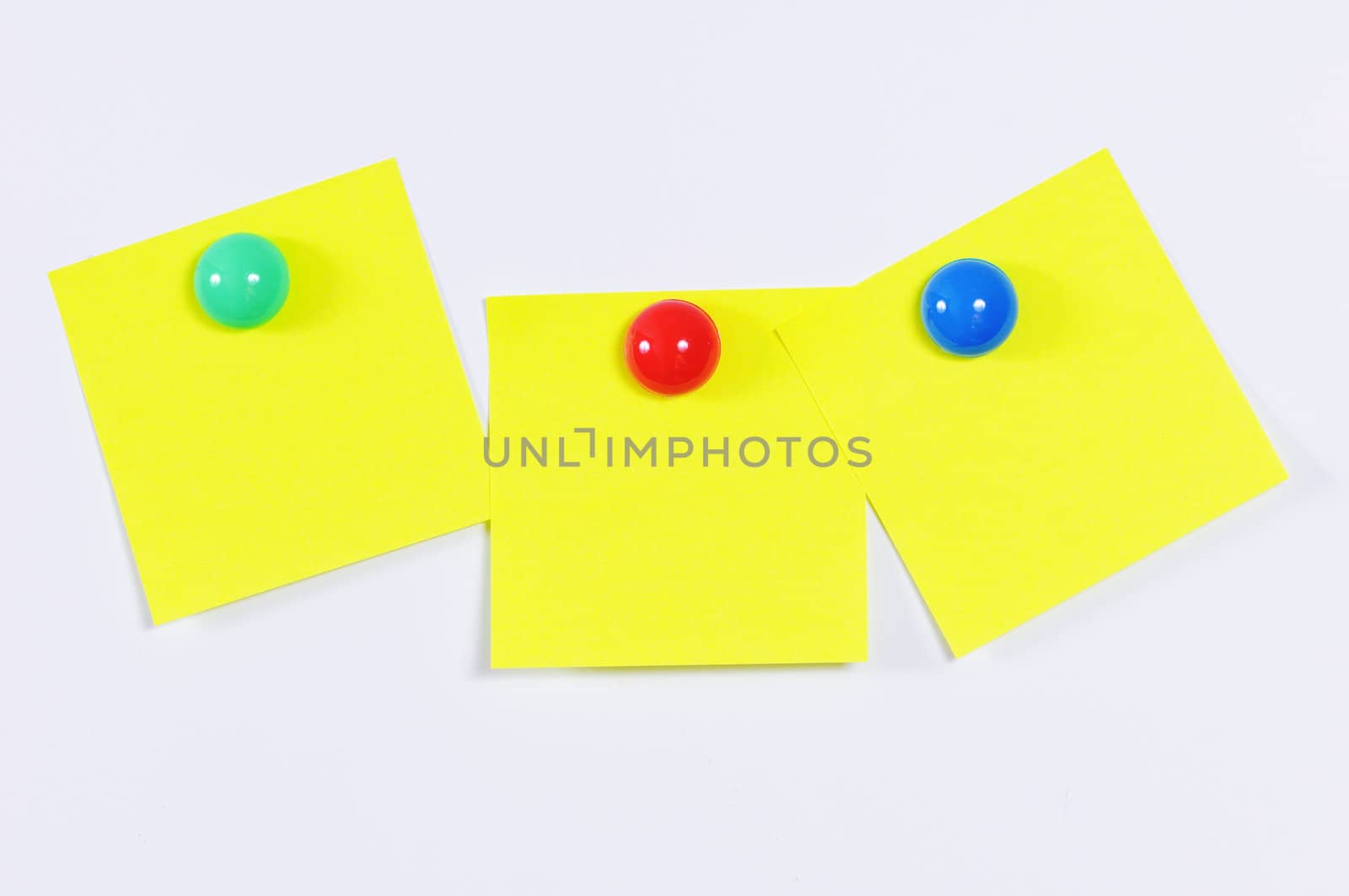 Yellow reminder notes with multicoloured pin  on the white wall
