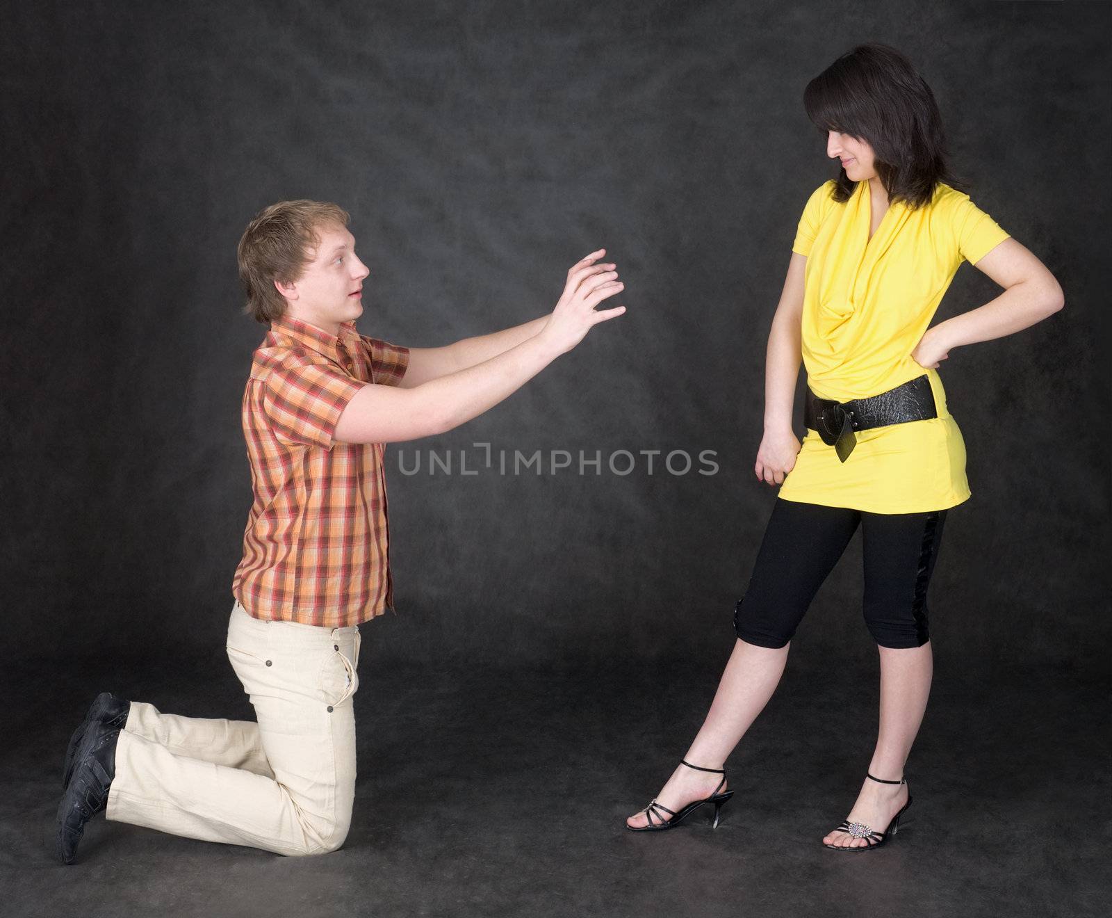 The man is kneeling to the young woman