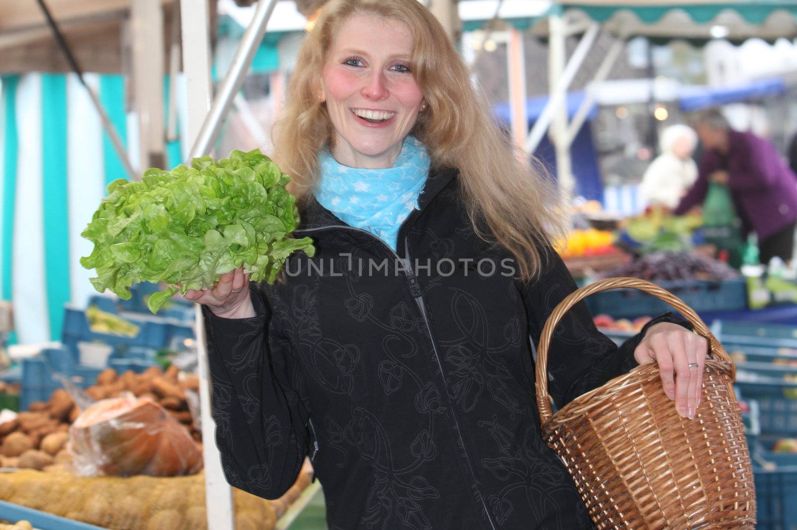 Young blond woman at the market with a fresh salad in his hand and smiling
