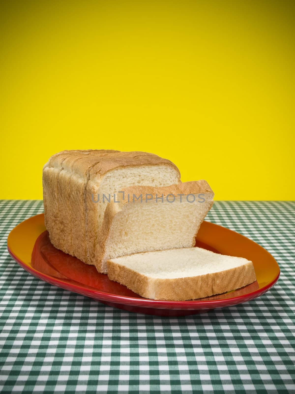 A loaf of sliced bread served on a red platter.