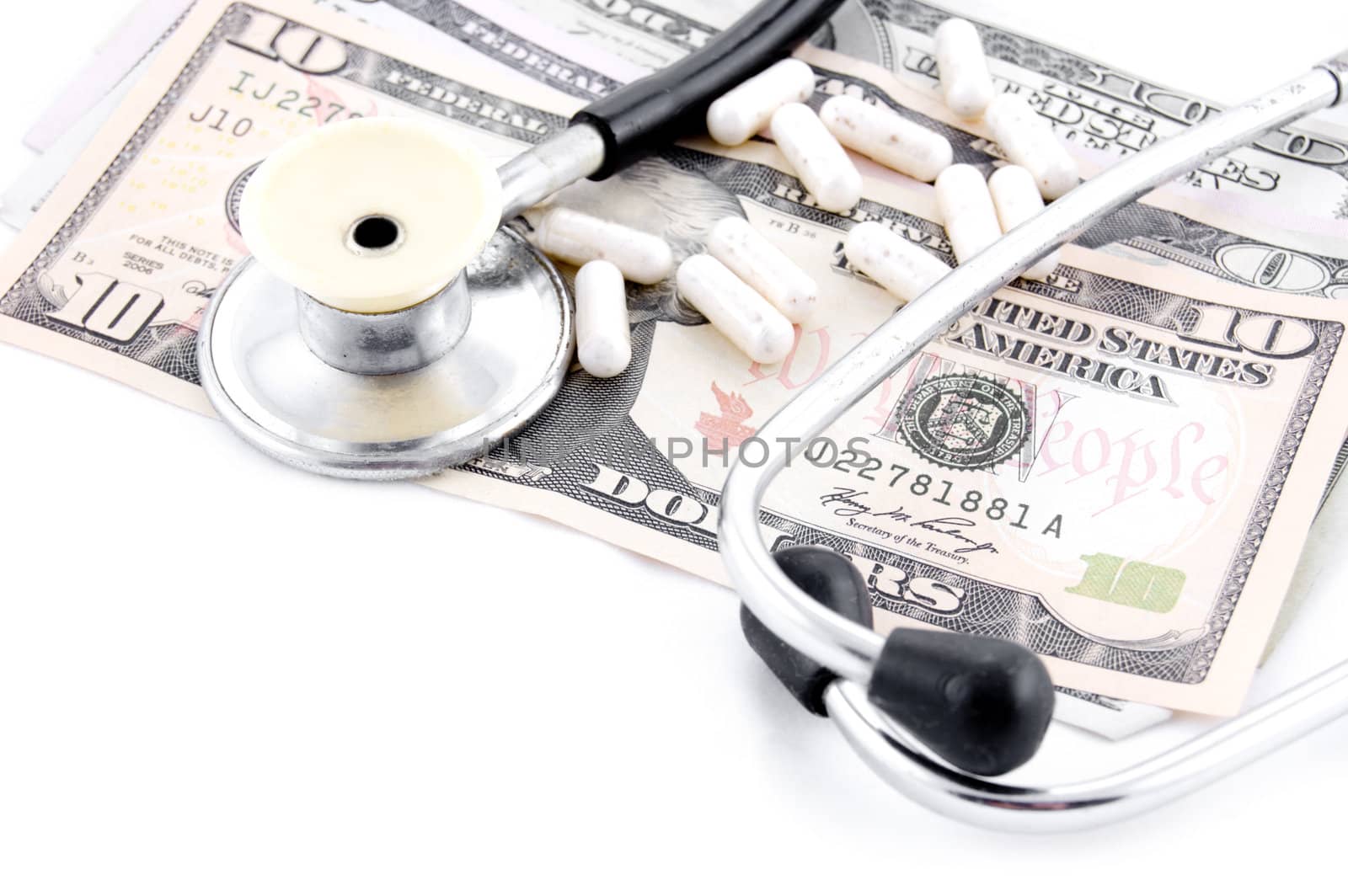 Stethoscope and some pills on dollars over white
