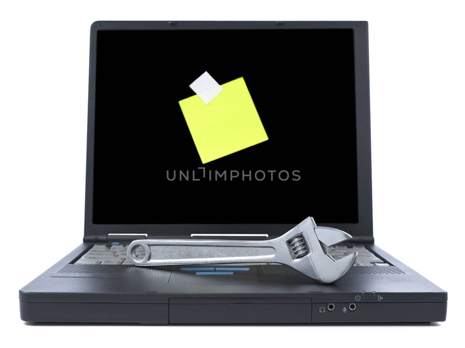 Laptop with a yellow sticky note and a spanner over the keyboard. Isolated on white.