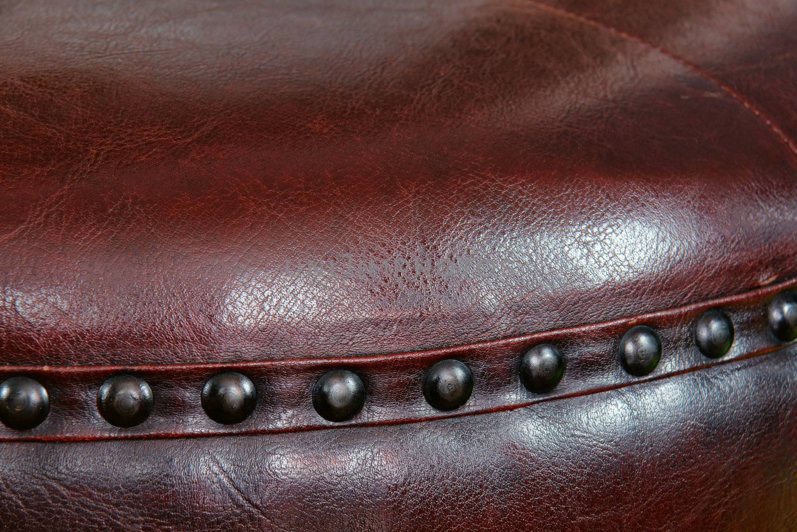 Nail head beading of deep rich chocolate brown leather round ottoman footstool.