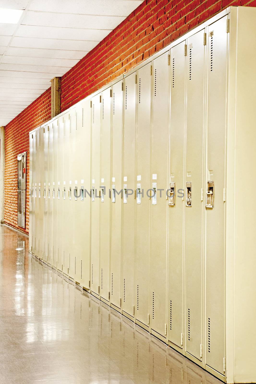 Perspective shot of a row of  lockers in the hallway of a brick wall school. 
