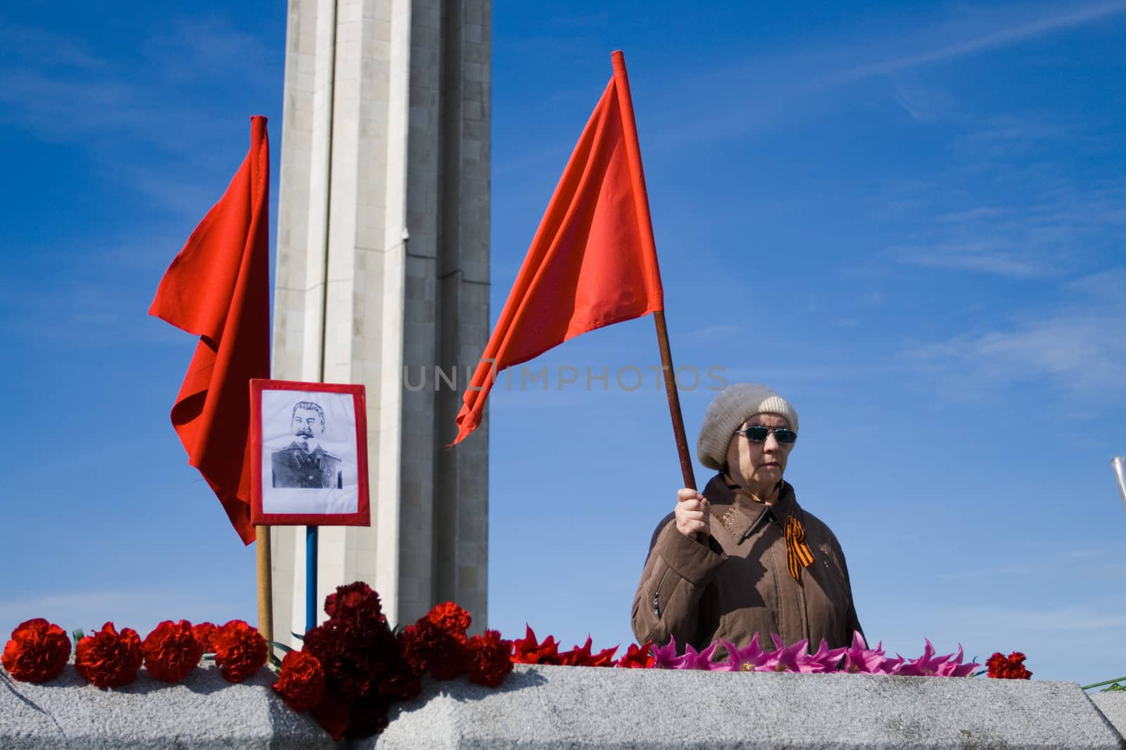 RIGA, LATVIA, MAY 9, 2008: Old soviet woman with red flag and picture of Stalin Celebrating May 9 Victory Day (Eastern Europe) in Riga at Victory Memorial to Soviet Army