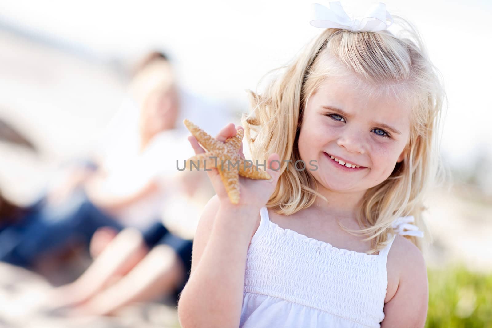 Adorable Little Blonde Girl with Starfish at The Beach.
