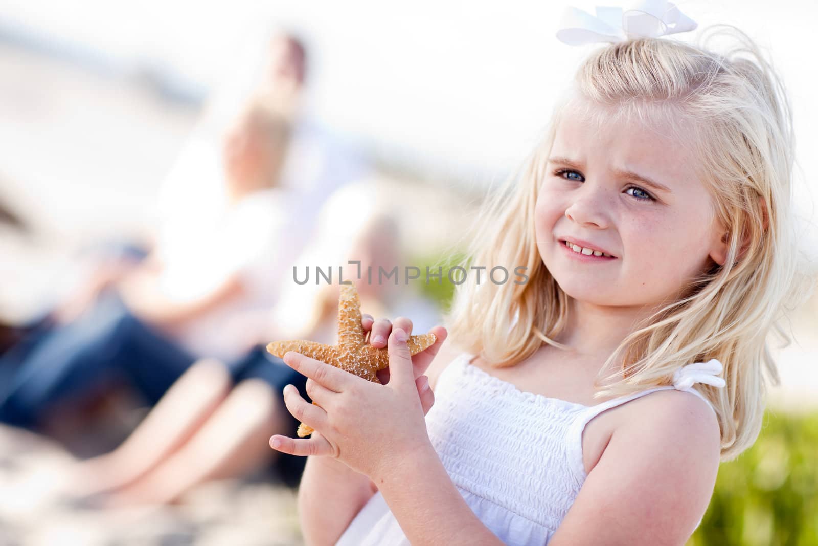 Adorable Little Blonde Girl with Starfish at The Beach.
