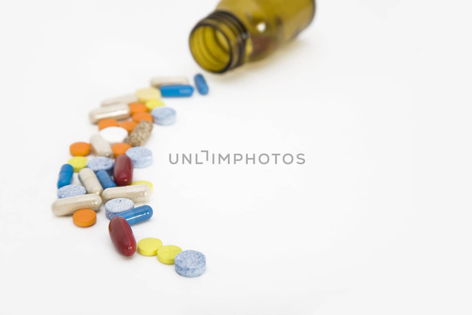 a colorful stream of pills coming from a pill bottle - on a white background