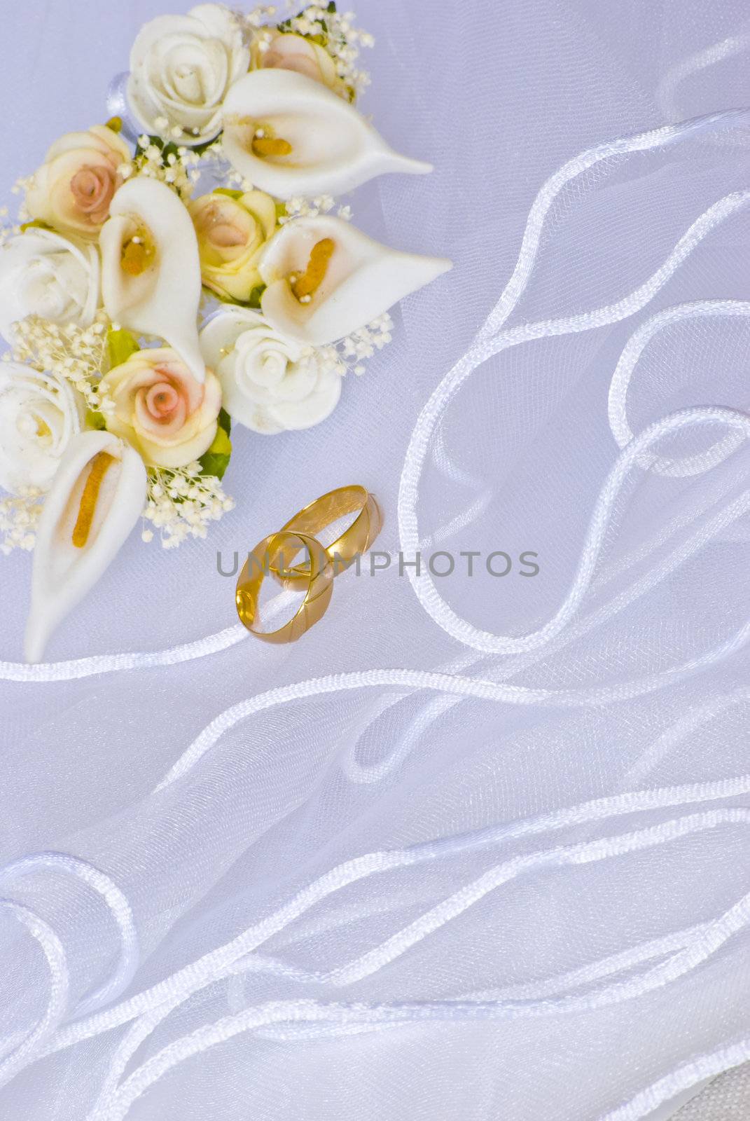 wedding rings and flowers decorations over bridal veil