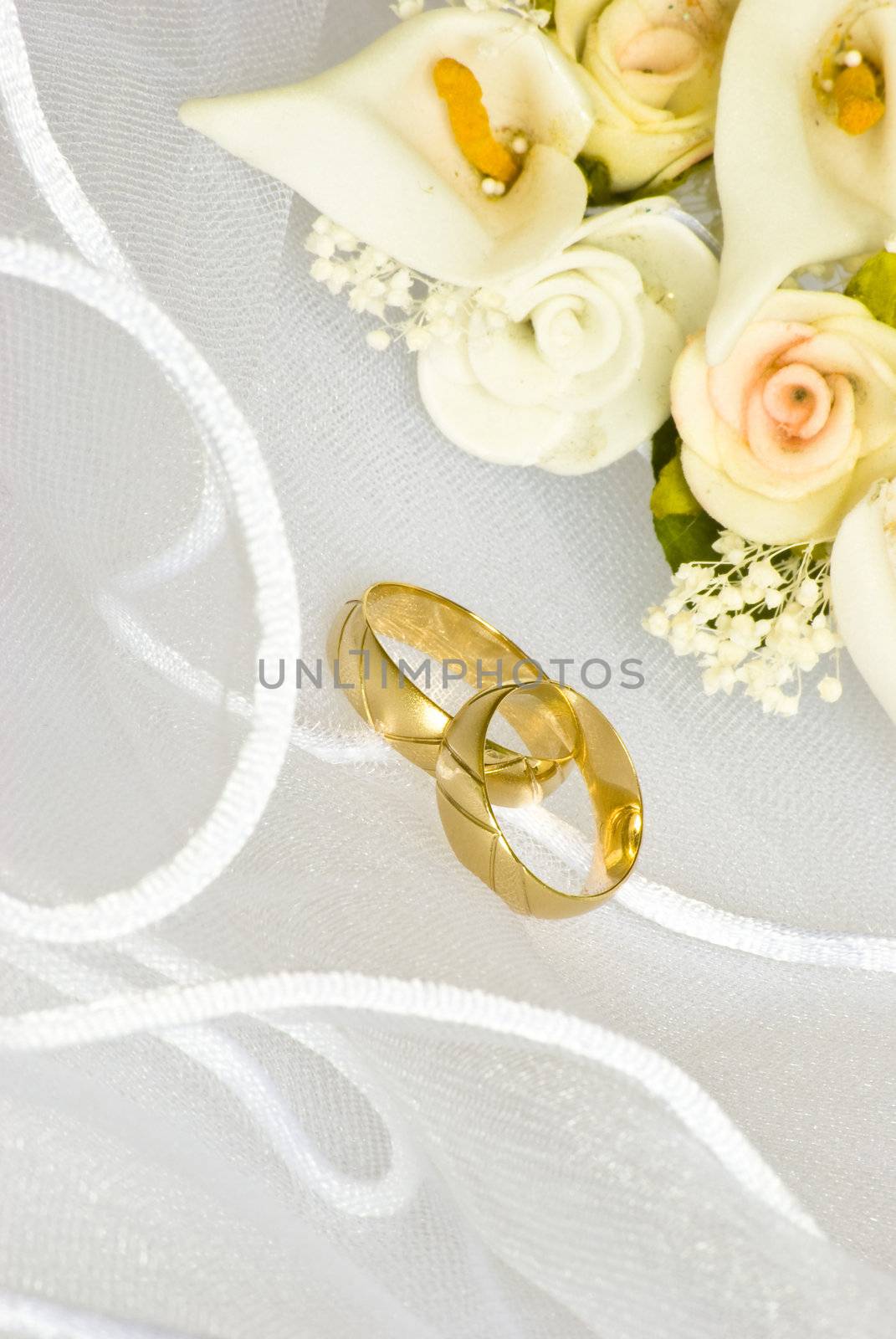 wedding rings and flowers decorations over bridal veil