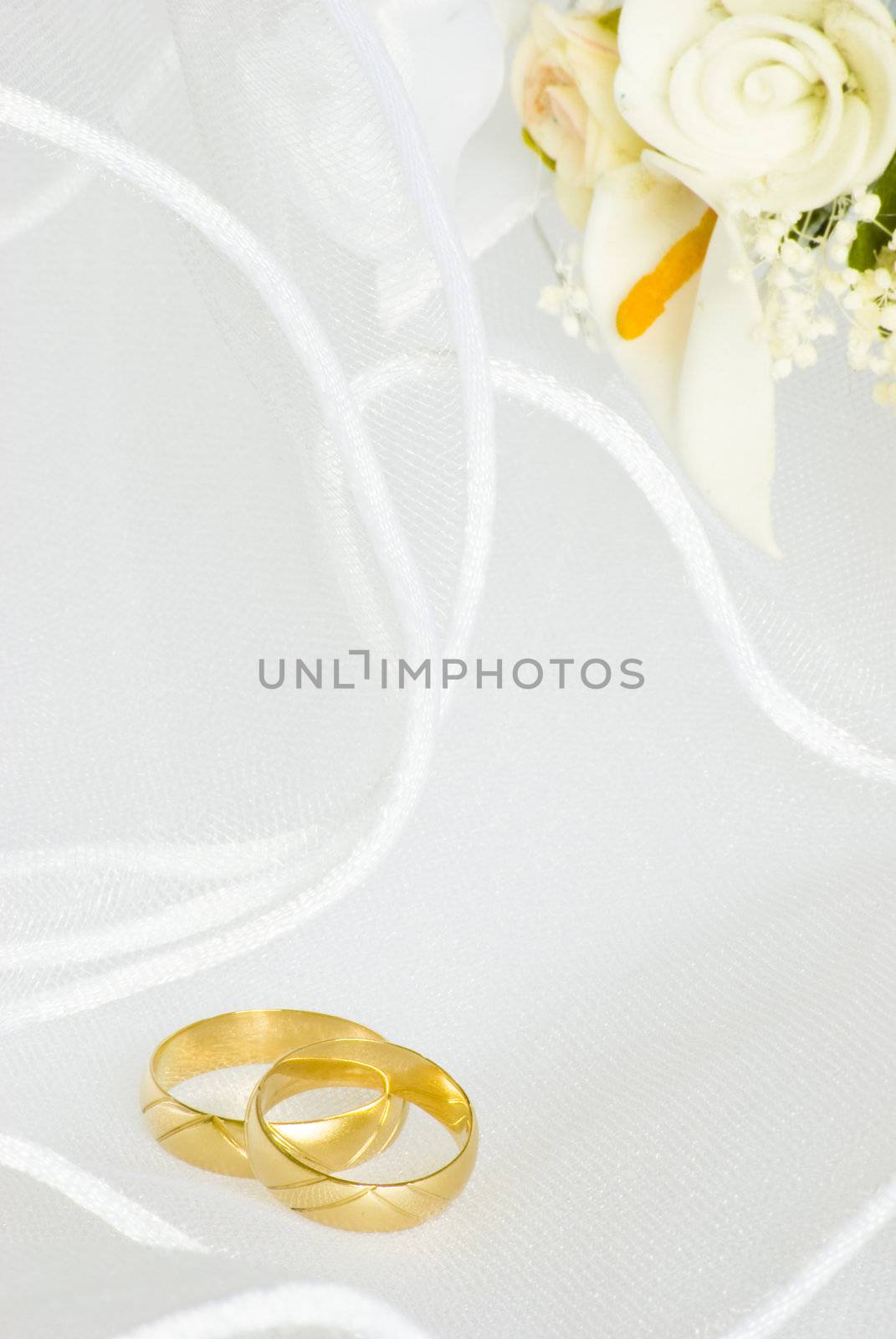 wedding rings and flowers decorations over bridal veil