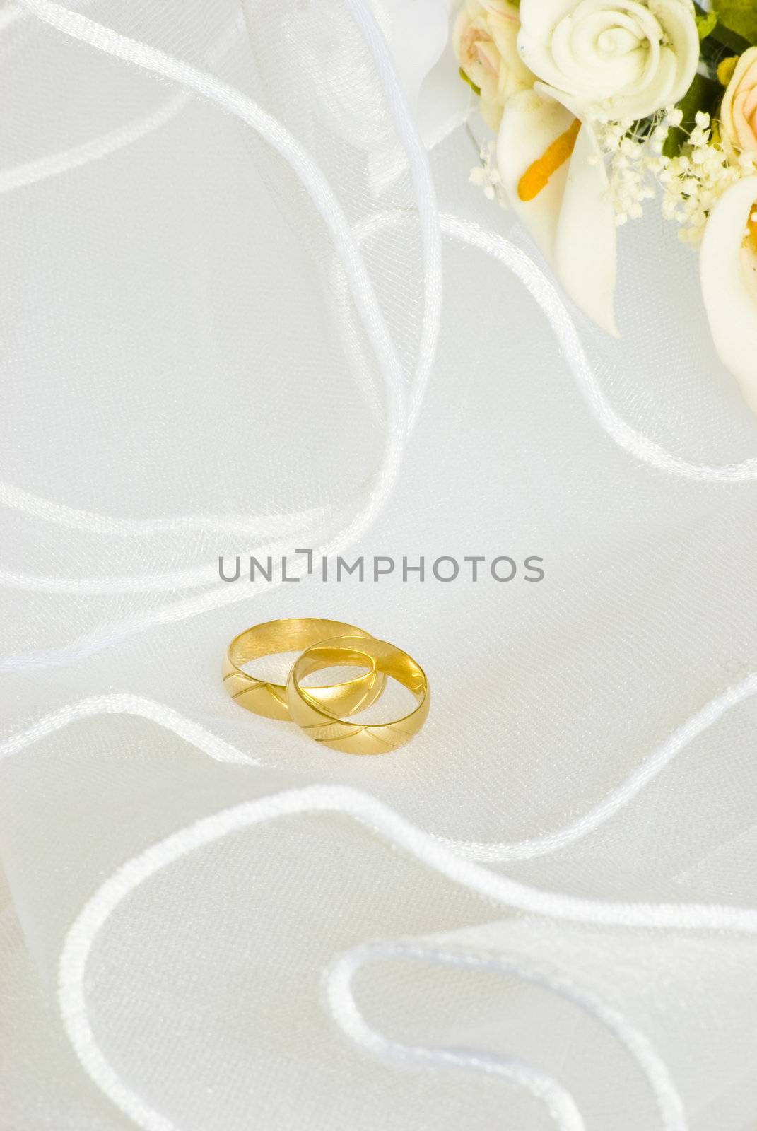 wedding rings and flowers decorations over bridal veil