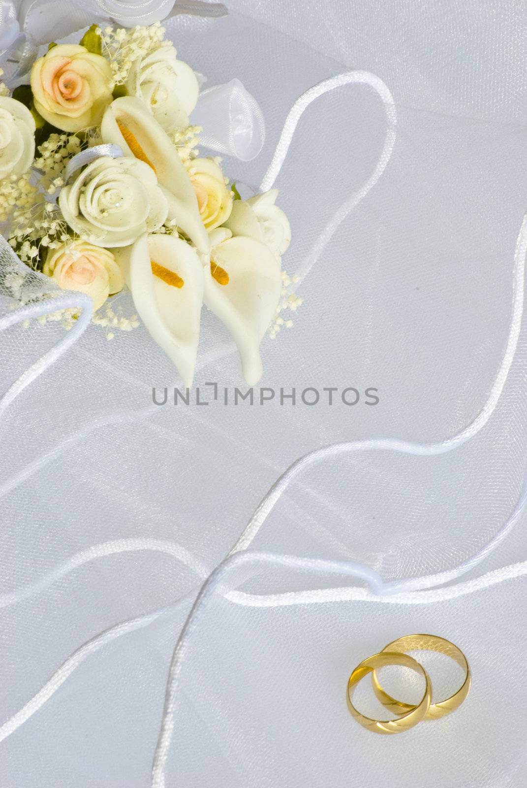 wedding rings and flowers decorations over bridal veil