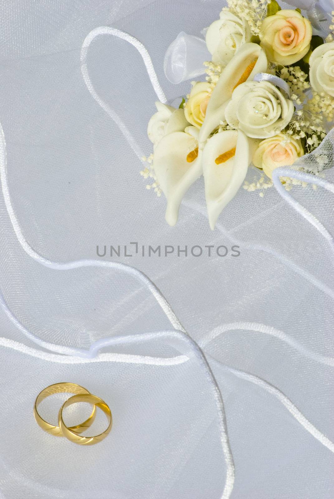 wedding rings and flowers decorations over bridal veil