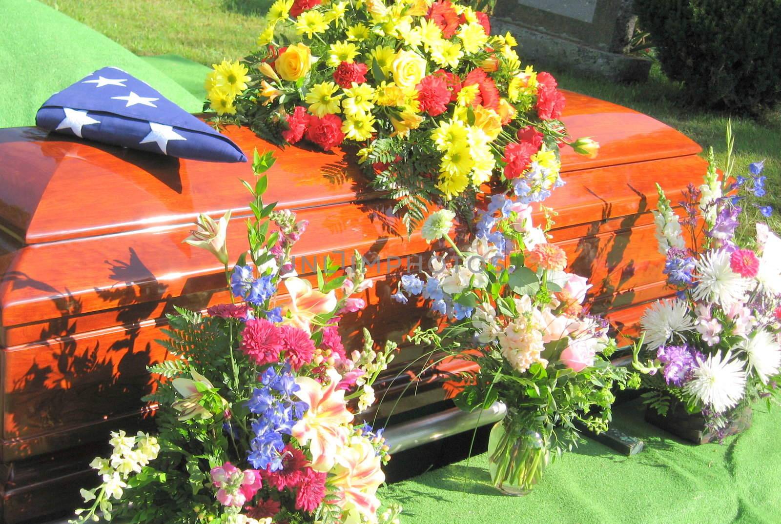 at graveside, flowers and the US flag honor the casket of a US military veteran