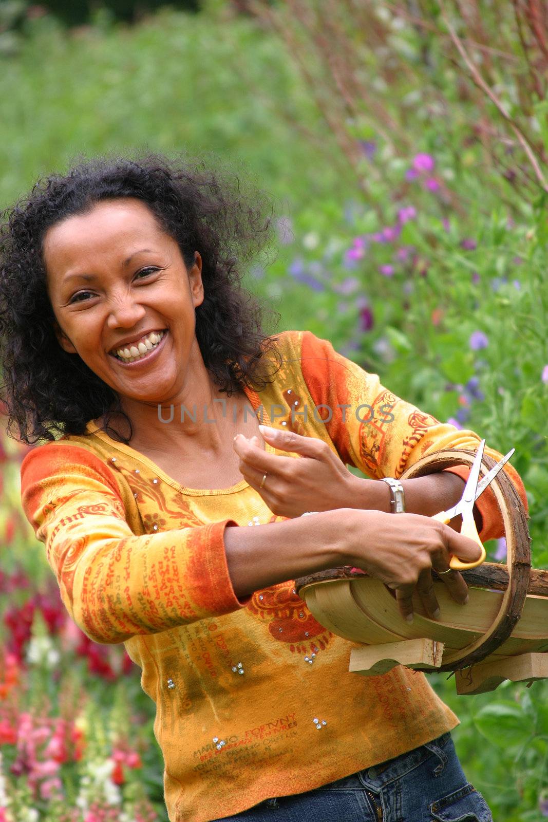 Pretty woman with flower basket cutting flowers in the garden