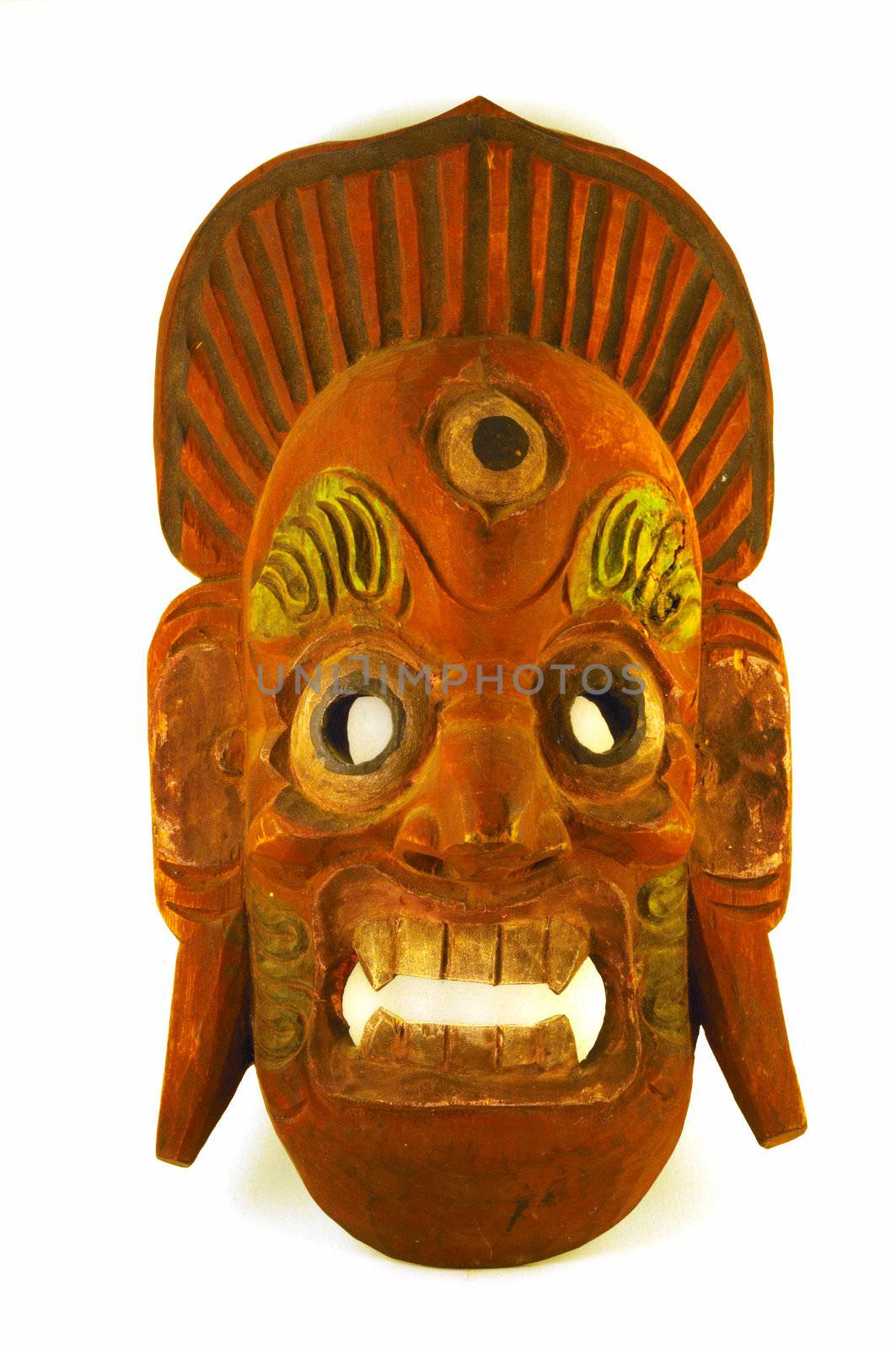 A wooden mask painted brick red and sage green, with fierce teeth and a third eye.  A crown surmounts the grimacing face.