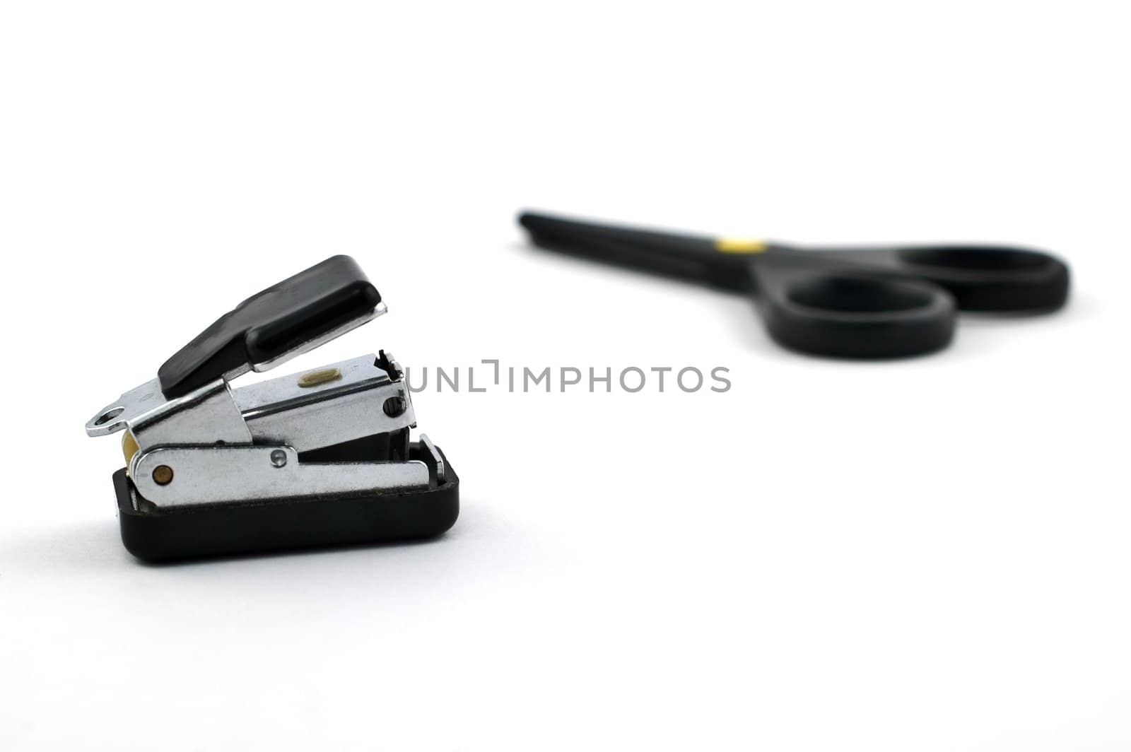 Stapler with safe scissors in the background isolated on white with shallow depth of field