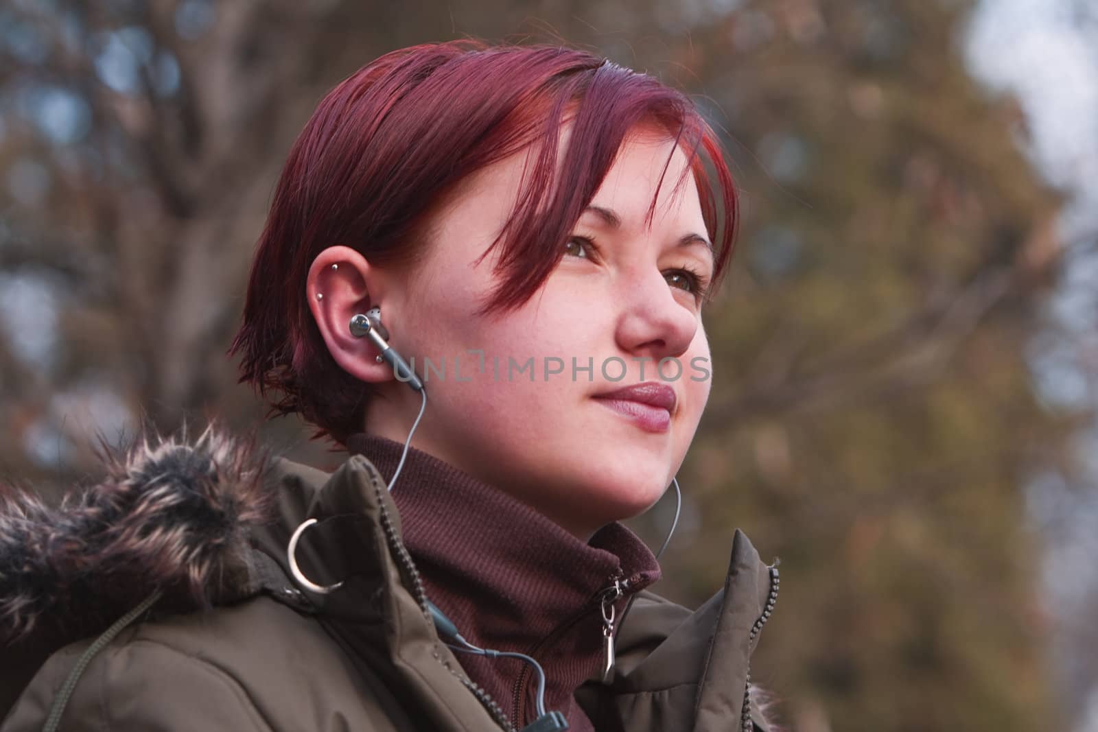 Redheaded girl listening to music in an autumn park.Shot with Canon 70-200mm f/2.8L IS USM