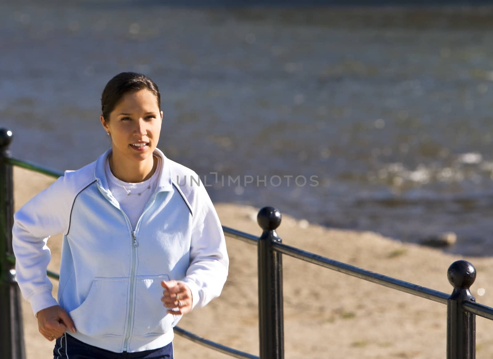 Image of a young woman running on the riverside.Shot with Canon 70-200mm f/2.8L IS USM