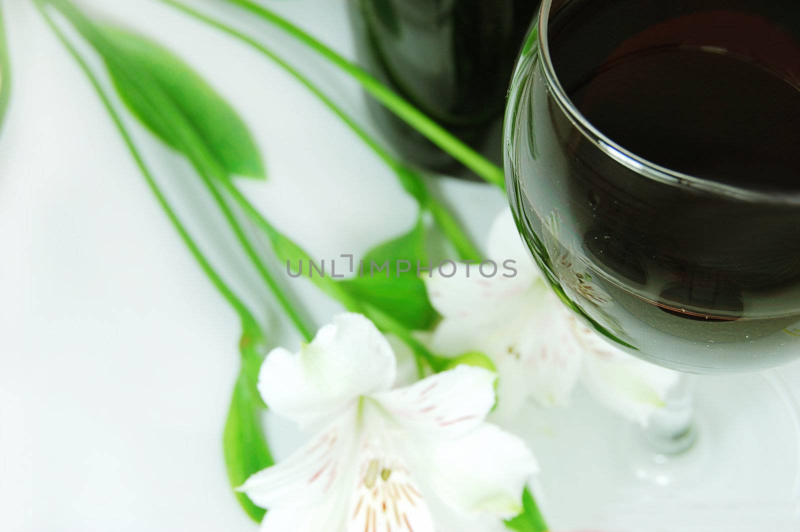 glass of red wine, bottle and white amaryllis