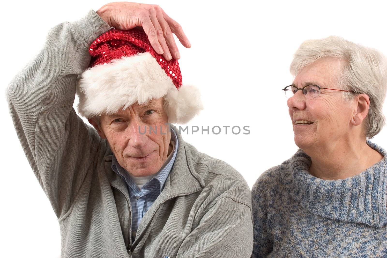 Elderly man checking if his santa hat is sitting properly