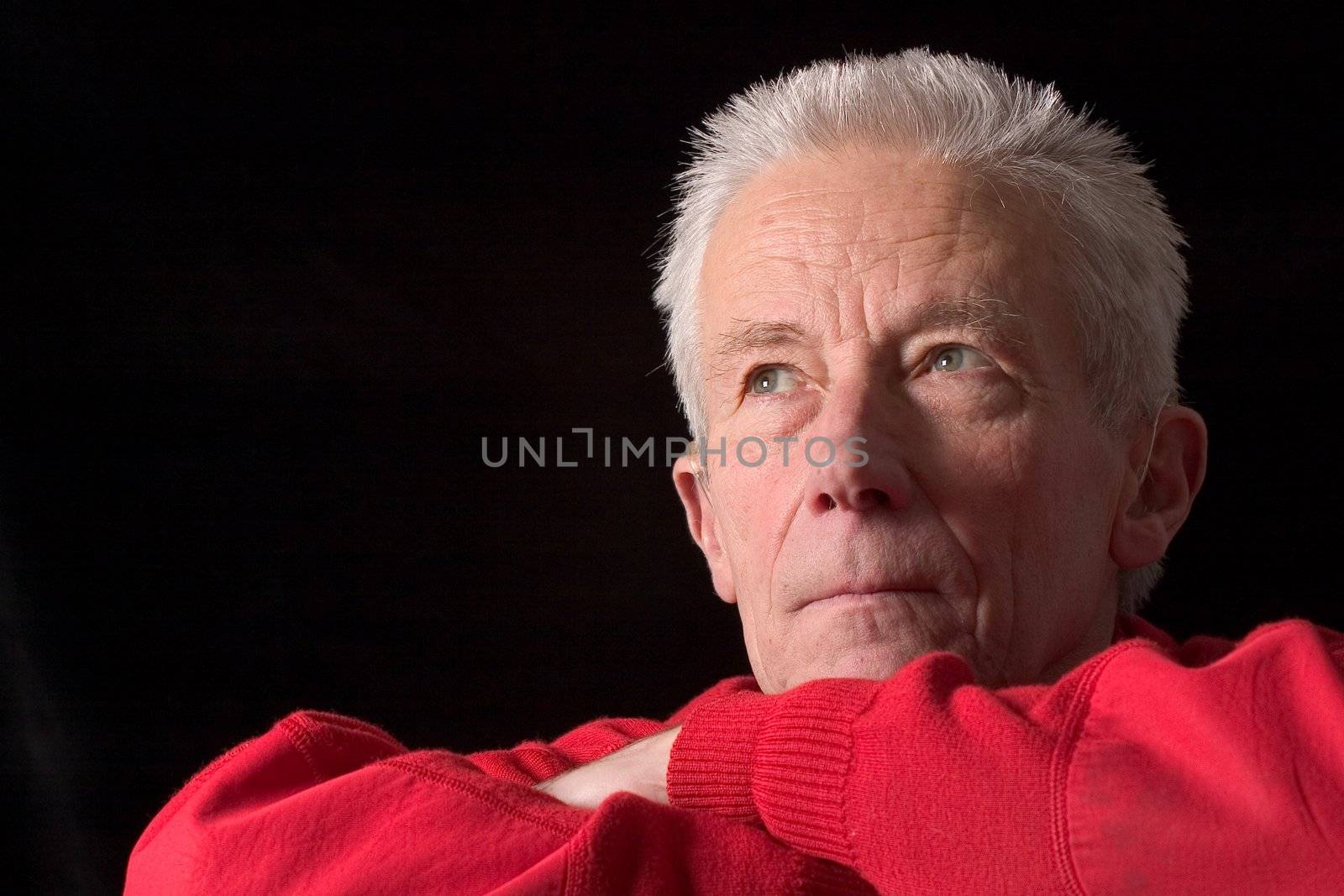 Handsome older man staring into the distance on black background