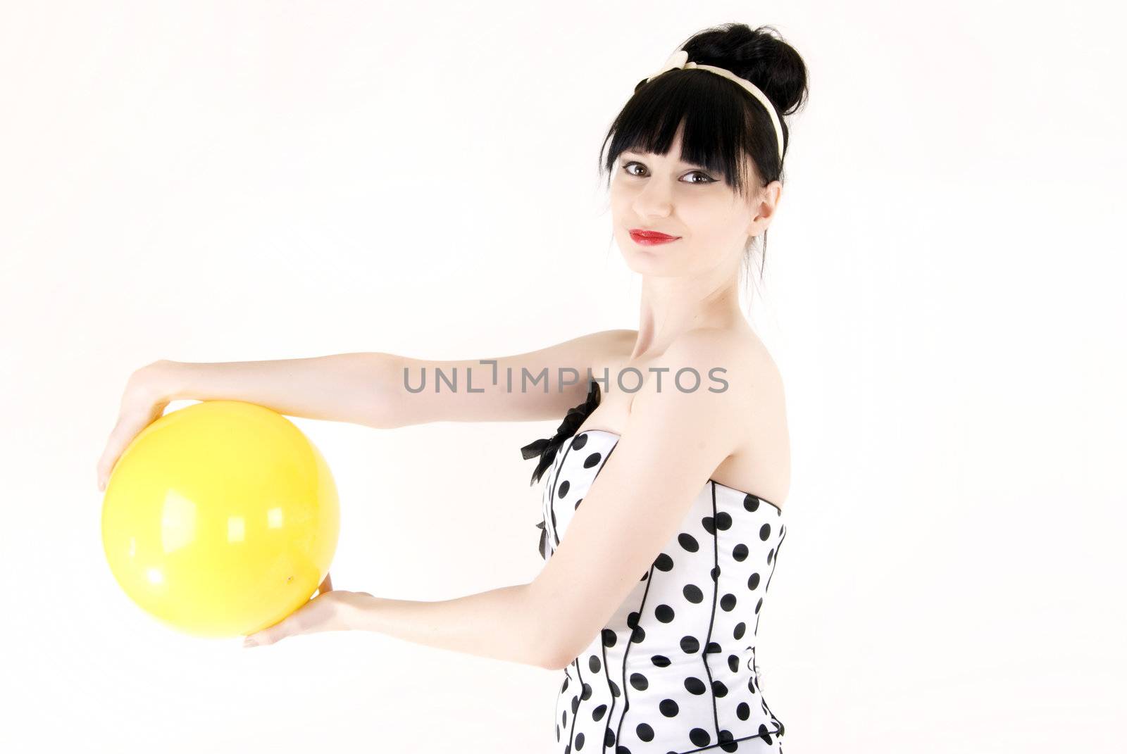 Portrait of a young beautiful brunette posing with yellow ball