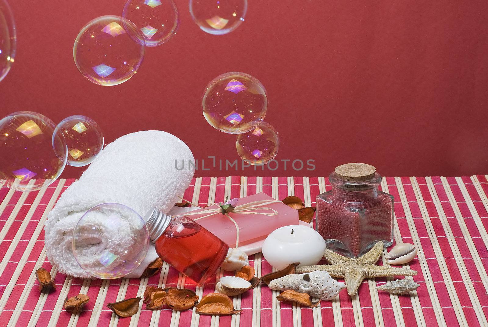 Still life about spa with some hygiene items in red and soap bubbles.