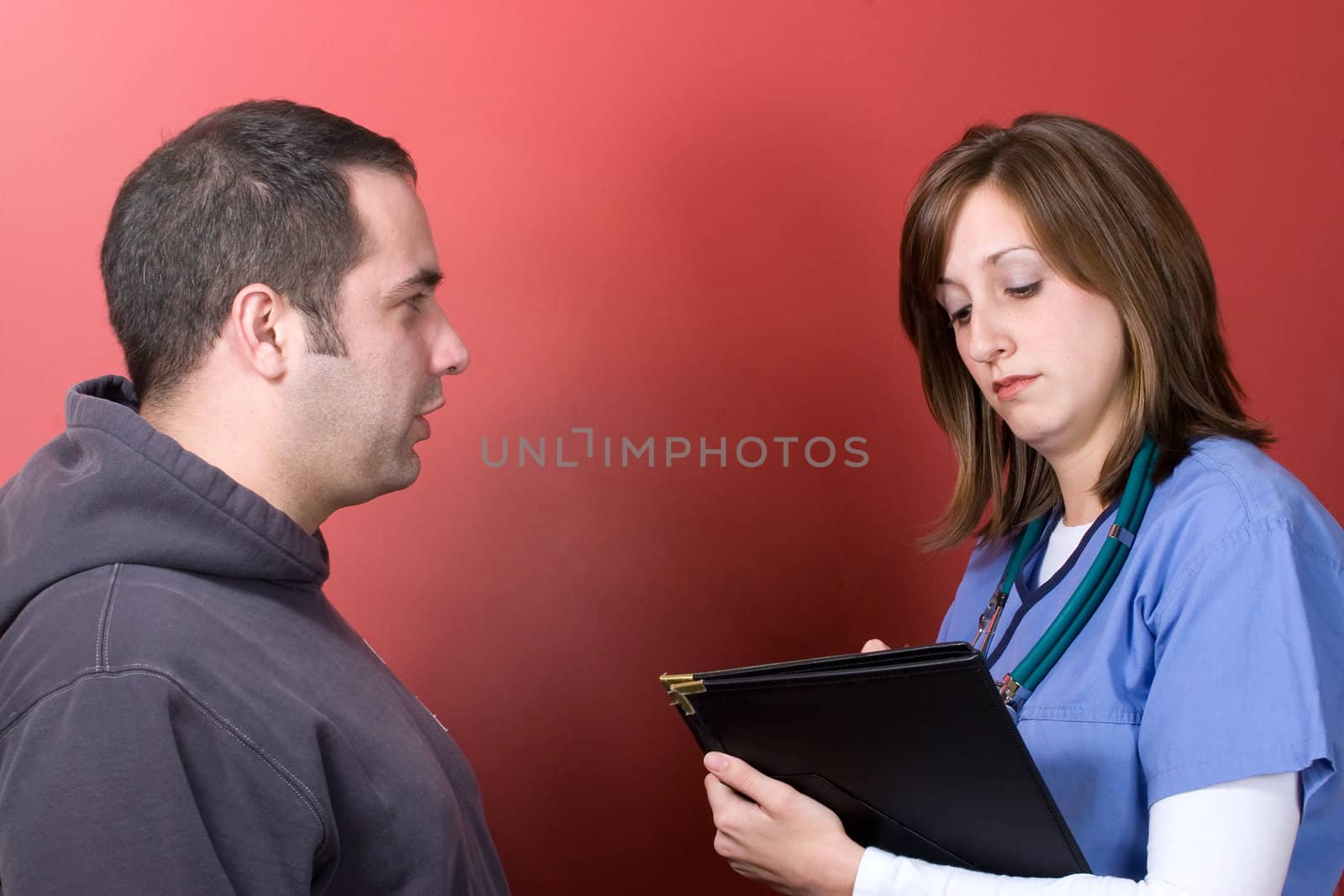 A young nurse talks to a concerned patient during his visit.