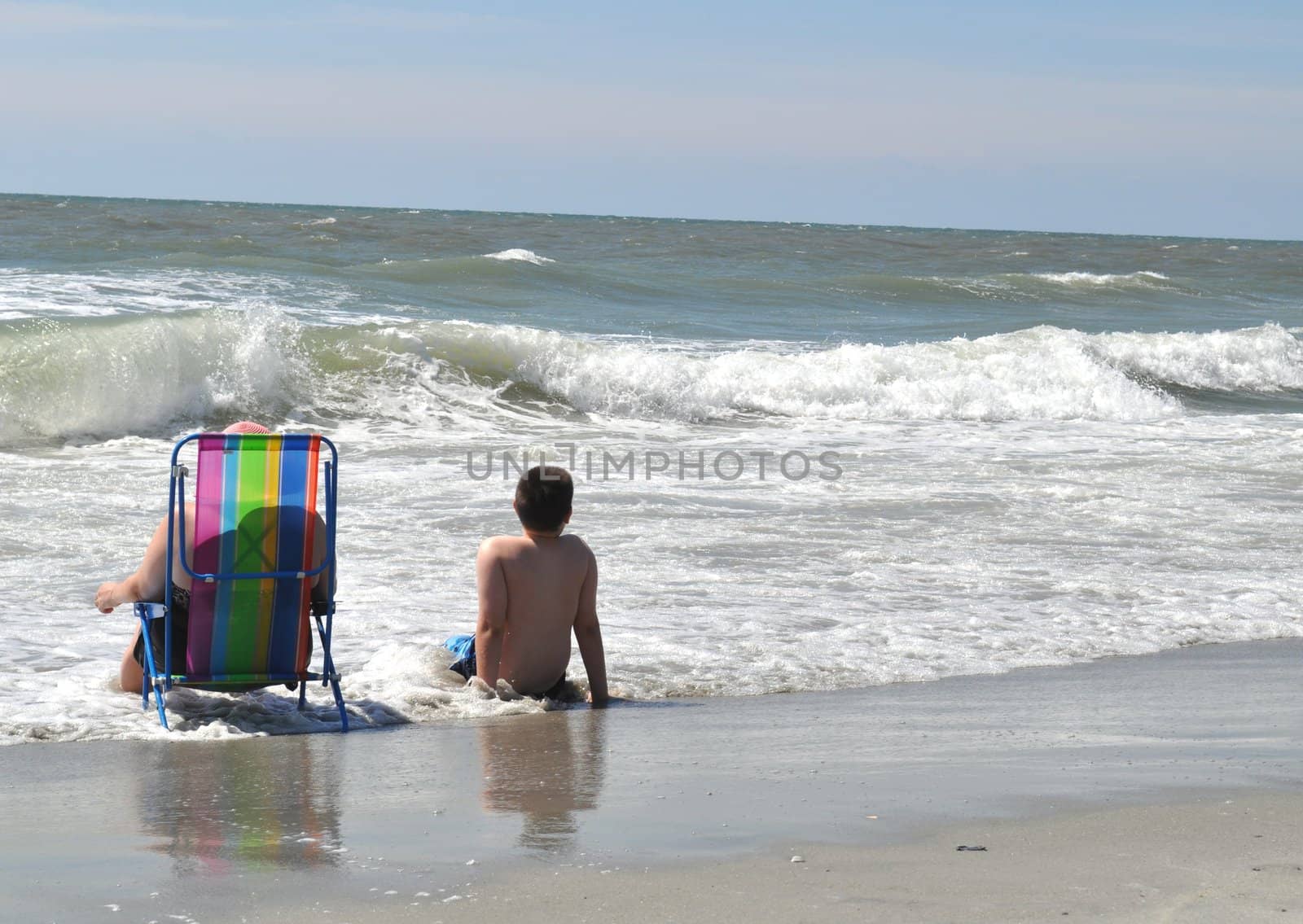 Mom and son sit on beach by RefocusPhoto