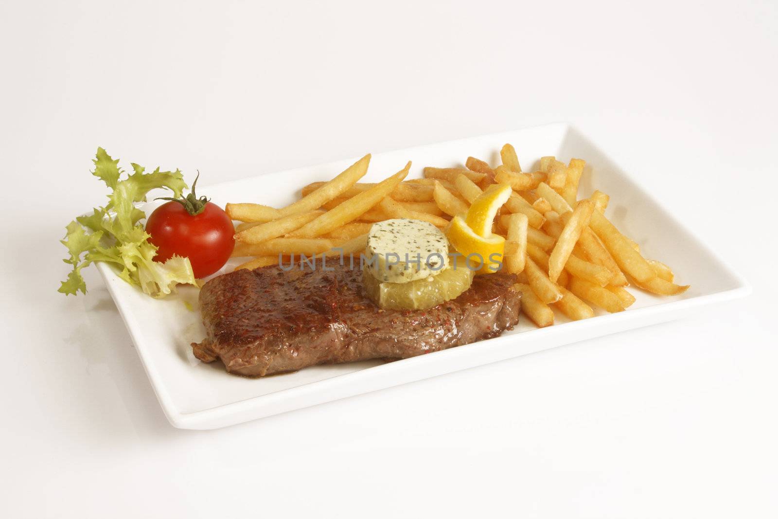 Grilled beef steak with french fries and sauce served in plate.