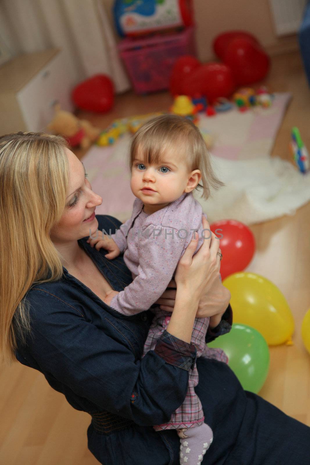 Young mother with her baby lovingly in her arms, at home in the nursery
 