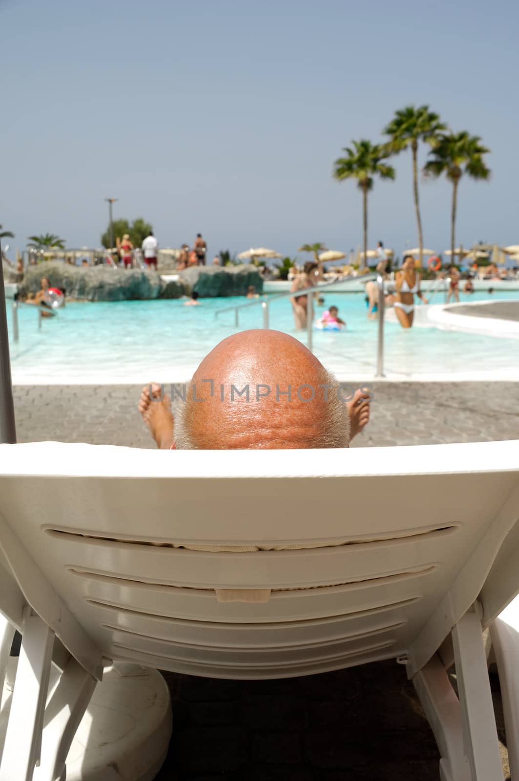 Bald headed man relaxing by the pool