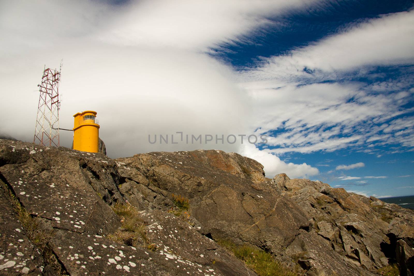 Blue sky white clouds. Small orange lighthouse - Hvalnes, Iceland