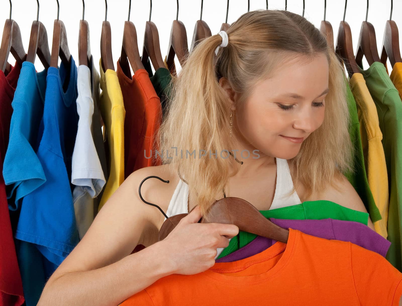 Girl standing near the rack of colourful clothing, choosing clothes to buy.