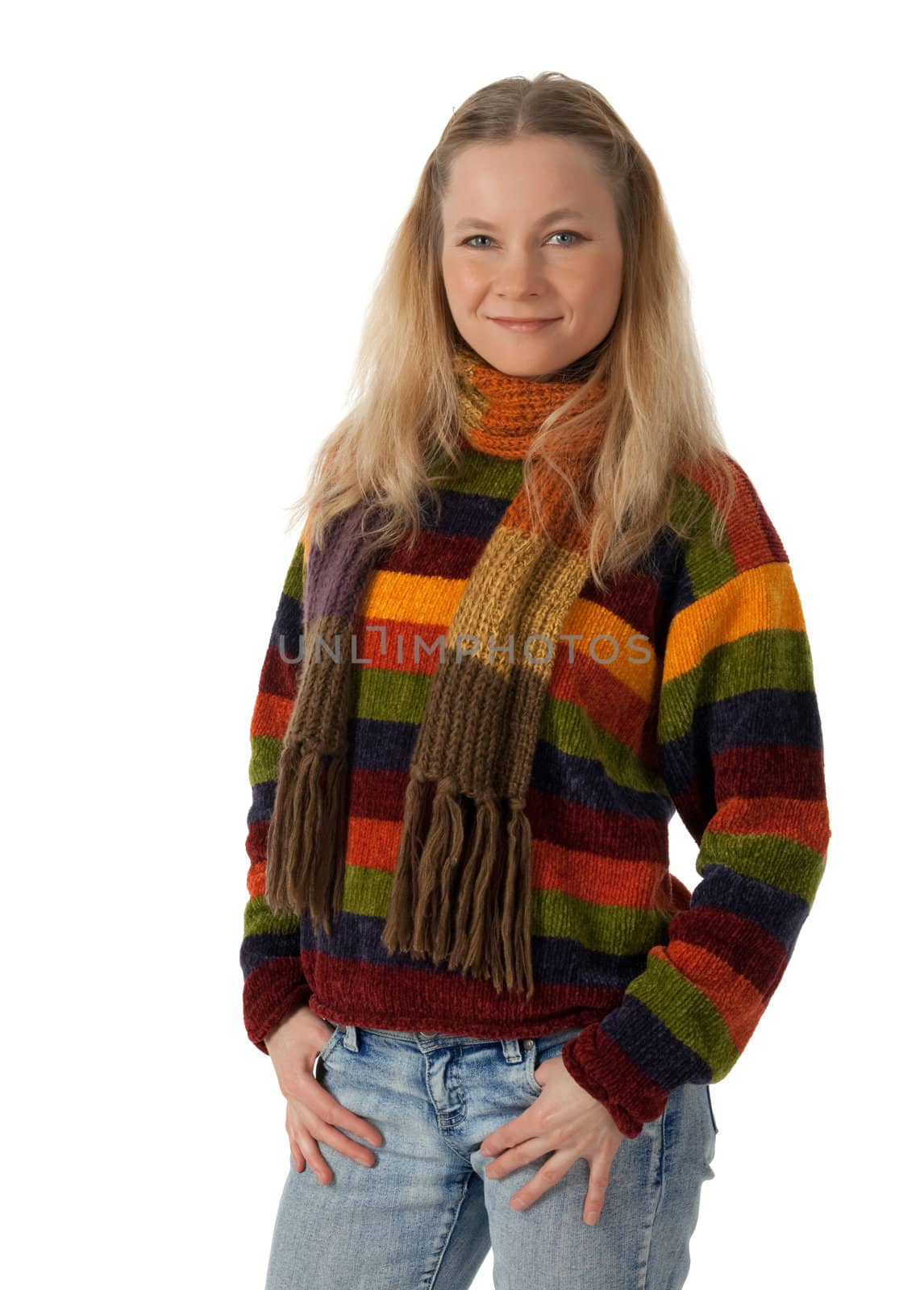Smiling young woman wearing striped sweater and scarf, holding hands in pockets.