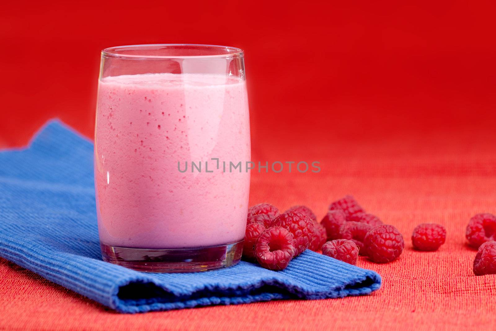 A fresh fruit raspberry smoothie isolated on red and blue